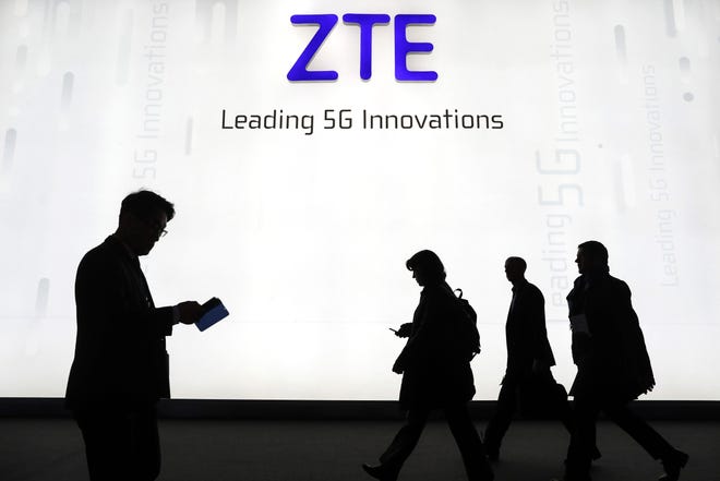 Attendees pass by the ZTE Corp. stand at the Mobile World Congress (MWC) in Barcelona on Feb. 26, 2018. MUST CREDIT: Bloomberg photo by Simon Dawson