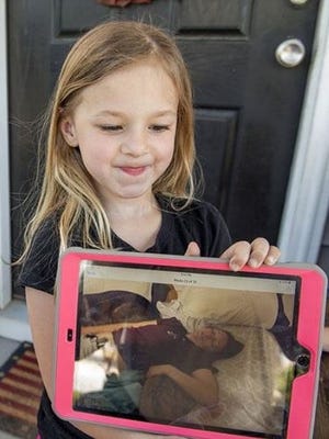 Brooklynn Decker, 5, shows a picture of her mom, Samantha Decker, in a diabetic coma while her father, Brandon Decker, was deployed to Camp Atterbury, Indiana, on April 24. [Lewis Perkins/Paraglide]