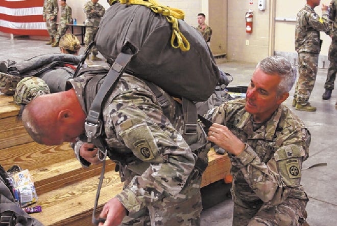 82nd Airborne Division chaplain, assists Master Sgt. Robert Blalock, the 82nd Airborne Division master religious affairs noncommissioned officer, put on his parachute inside personnel shed 1 at Pope Army Airfield at Fort Bragg, May 8