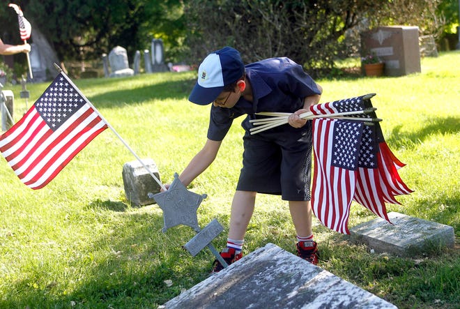 Dale Damron of Pack 506 places a flag on veterans' graves Wednesday at Ashland Cemetery. Ashland will have a Memorial Day ceremony at the cemetery following a 10 a.m parade on Monday, May 28. Villages throughout Ashland County will have similar observances on Memorial Day.