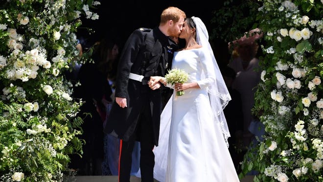 Britain’s Prince Harry, Duke of Sussex kisses his wife Meghan, Duchess of Sussex as they leave from the West Door of St. George’s Chapel, Windsor Castle, in Windsor on May 19, 2018 in Windsor, England. (Photo by Ben Stansall, WPA Pool/Getty Images)