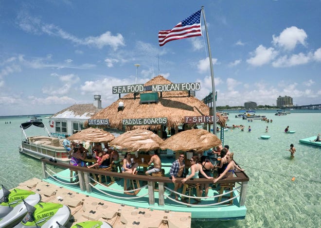 Customers enjoy a sunny day on the deck of Waterworld, one of several floating businesses that serve crowds at Crab Island in Destin.

[DEVON RAVINE/DAILY NEWS]