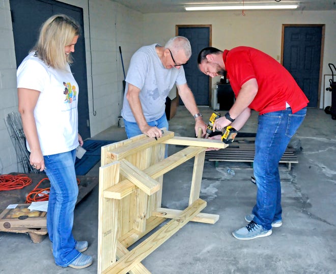 Jennifer Sanders, left, an early childhood mental health consultant from The Counseling Center of Wayne and Holmes Counties, watches Titus Yoder and Josh Miller put together a preschool-size picnic table. Sanders got representatives from the Home Builders Association of Wayne and Holmes Counties and Lowe’s in Wooster to build picnic tables and garden boxes for local day care centers. Sanders provides consultation to caregivers who work with infants to children who are 6 years old on social and emotional skills and works with teachers and administrators and occasionally families who are struggling. She said the picnic tables will be a great way to enjoy the outdoors for snack time or play as children sit around the build relationships, and the garden boxes will foster self-regulation and initiative among young children.