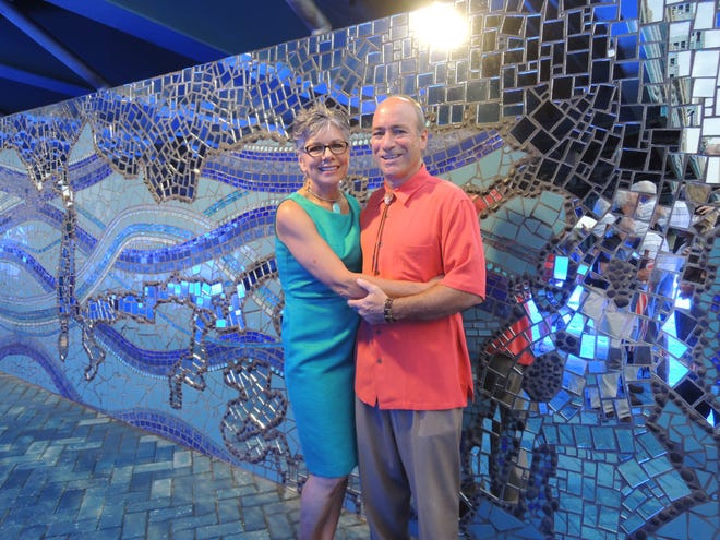Downtown Art. Artists Kate and Kenny Rouh of RouxArt pose in front of the completed moasic mural "Mirrored River: Where Do You See Yourself?" along the Southbank Riverwalk.
