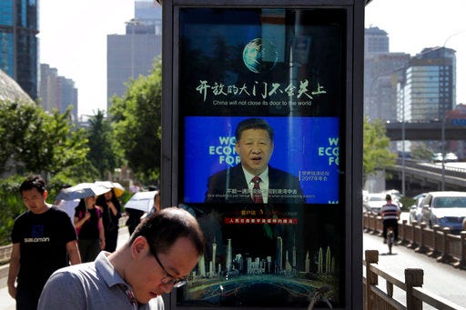 People walk by an electronic display panel advertising a video footage of Chinese President Xi Jinping speaking at the World Economy Forum on a street in Beijing, Wednesday, May 30, 2018. Ahead of a visit to China by U.S. Commerce Secretary Wilbur Ross for talks on a simmering trade dispute, an American business group called on Beijing on Wednesday to allow the same access to its state-dominated economy that Chinese companies have to U.S. markets. (AP Photo/Andy Wong)