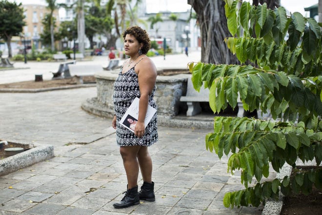 Miliana Montanez, 29, poses for a portrait with a memorial book for her mother in Caguas, Puerto Rico. Montanez's mother, Ivette Leon, died weeks after Hurricane Maria hit the island, something her family says was the result of crippled infrastructure. MUST CREDIT: Photo by Erika P. Rodríguez for The Washington Post.
