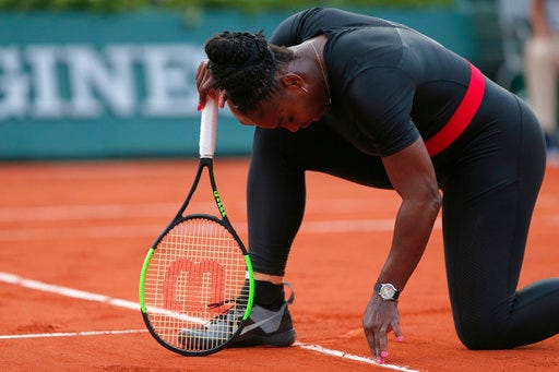Serena Williams of the U.S. cleans the baseline with her fingers during her second round match of the French Open tennis tournament against Australia's Ashleigh Barty at the Roland Garros stadium in Paris, France, Thursday, May 31, 2018. (AP Photo/Thibault Camus)