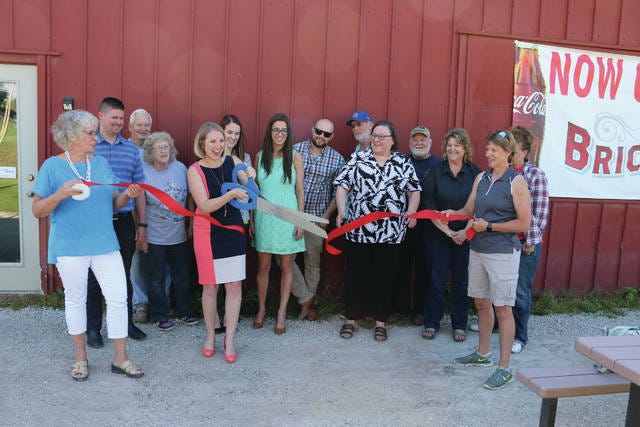 Ashley Miller (holding scissors) cuts the ribbon for her new Adel business, Transformational Wealth. The Ribbon Cutting was held at Brickyard Burgers and Brews on May 31. PHOTO BY CLINT COLE/DALLAS COUNTY NEWS