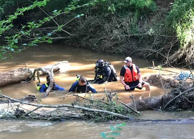 Divers search the area underneath a fallen tree in McNutt Creek on Sunday. [Photo: Oconee County Sheriff's Office]