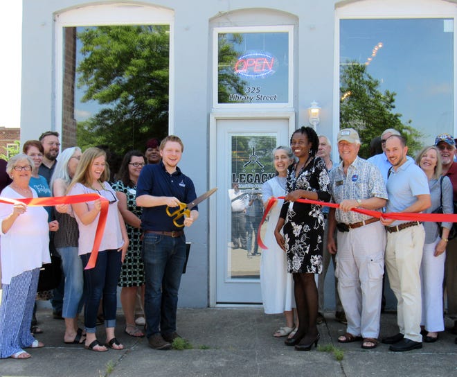 Owner Larry Hancock, left center, wields the golden scissors at the Legacy Roasting Company ribbon-cutting ceremony on June 1, 2018, surrounded by Hopewell officials and community members. The company is located at 325 Library St., Hopewell. [Kate Gibson/progress-index.com]