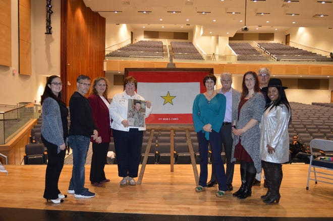 From left, school board members Rachel Fingles, Marc Cohen and Stephanie Gonzalez Ferrandez; Judith Faunce; Samantha Faunce Sand; Richard Faunce; school board member Heather Nicholas; alumni association President Ray Guim and school board member Vanessa Woods pose with the Gold Star flag the Faunce family presented to the district in honor of Army Capt. Brian Faunce, a 1992 Bensalem graduate who was killed in action in Iraq. [Courtesy of Bensalem Township School District]