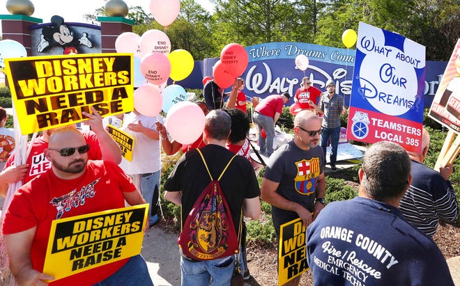 In this March 23 file photo, unionized workers for Walt Disney World and their supporters march and chant in front of Disney hotel property in Orlando, Fla. Walt Disney World didn't violate the law when it withheld $1,000 bonuses to workers in a coalition of unions currently renegotiating wages, even though it paid the bonuses to other Disney workers who are either unorganized or represented by other unions, the National Labor Relations Board ruled last week.