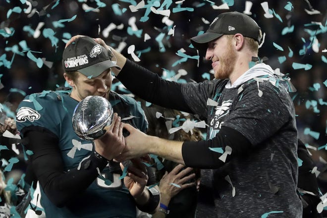 FILE - In this Feb. 4, 2018 photo, Philadelphia Eagles quarterback Carson Wentz, right, hands the Vincent Lombardi trophy to Nick Foles after winning the NFL Super Bowl 52 football game against the New England Patriots in Minneapolis. The Eagles won 41-33. President Donald Trump has called off a visit by the Philadelphia Eagles to the White House Tuesday due to the dispute over whether NFL players must stand during the playing of the national anthem. Trump says in a statement that some members of the Super Bowl championship team þÄúdisagree with their President because he insists that they proudly stand for the National Anthem, hand on heart.þÄù Trump says the team wanted to send a smaller delegation, but fans who planned to attend þÄúdeserve better.þÄù  (AP Photo/Frank Franklin II)