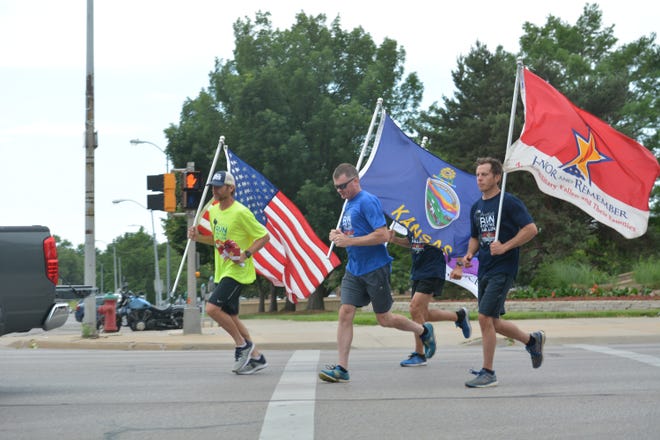 From left, Roger Haubold, Jared Beam and Eric Wenrich carry flags as they run through downtown Topeka on Monday afternoon as part of America's Run for the Fallen. [Phil Anderson/The Capital-Journal]