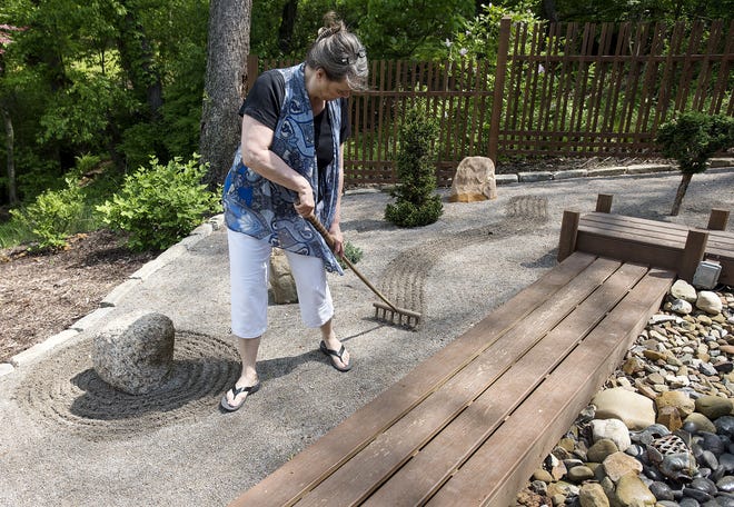 Lisa Story, founder and executive director of Hope Grows, uses a rake in a Japanese garden behind her home in Moon Township. [Kevin Lorenzi/BCT staff]