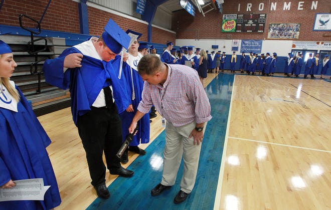 Scott Heavner used a metal detector to make sure graduates didn't have cellphones or keys in their pockets before they went onto the field for Cherryville High School's graduation ceremony last year. [Star file photo]