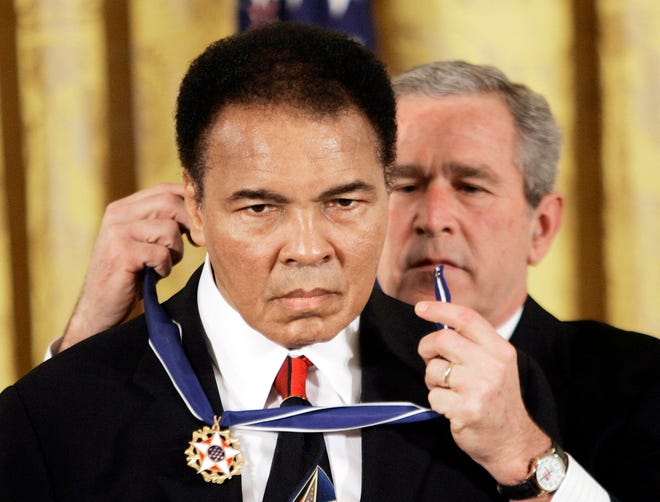 FILE - In this Nov. 2009 file photo, President Bush presents the Presidential Medal of Freedom to boxer Muhammad Ali in the East Room of the White House. President Donald Trump said he is thinking "very seriously" about pardoning Muhammad Ali, even though the Supreme Court vacated the boxing champion's conviction in 1971. (AP Photo/Evan Vucci)