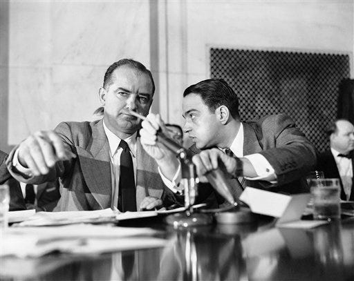 U.S. Sen. Joseph McCarthy, R-Wis., listens to his chief counsel, Roy Cohn, whose hand covers a microphone to prevent airing their conversation. The incident occurred in Washington, D.C., on April 23, 1954, during the second day of the Army-McCarthy hearings. [The Associated Press/File]