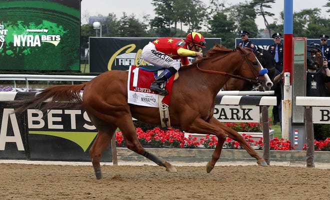 Justify, with jockey Mike Smith up, crosses the finish line to win the 150th running of the Belmont Stakes to become the 13th Triple Crown winner. [Julie Jacobson/The Associated Press]
