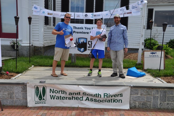 Motorized Boat Angler, 12 and under 1st Place þÄì Michael Hussey, Duxbury, Age 12, accepting his prize package from Tournament Chair Tad Beagley and committee member Caleb Estabrooks. Photo courtesy North and South Rivers Watershed Association.