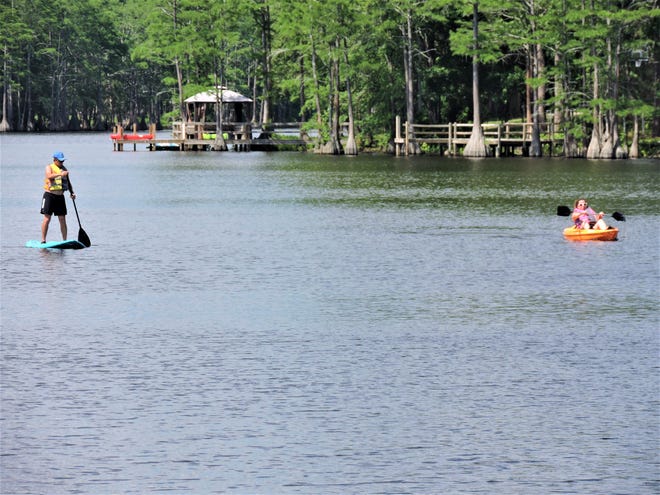 A standup paddler and a kayaker enjoy Hope Mills Lake. [Lisa Carter Waring/The Fayettteville Observer}