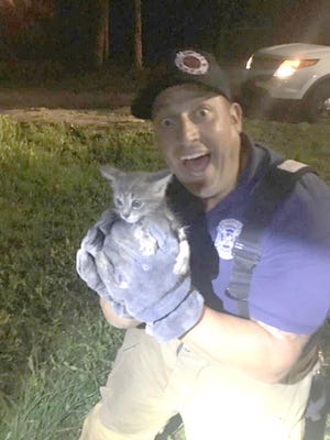 Ocean City-Wright firefighter Kevin Houston holds Penny after rescuing her from a storm drain Monday night. [SOCKS/CONTRIBUTED PHOTO]