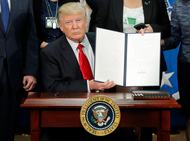 FILE - President Donald Trump holds up an executive order for border security and immigration enforcement improvements after signing the order during a visit to the Homeland Security Department headquarters in Washington, on Jan. 25, 2017. A survey conducted by The Associated Press-NORC Center for Public Affairs Research and MTV finds that parents and their kids agree about a lot of things when it comes to politics. Most in both generations disapprove of Trump, and 55 percent say they usually see eye to eye about politics. (AP Photo/Pablo Martinez Monsivais, File)