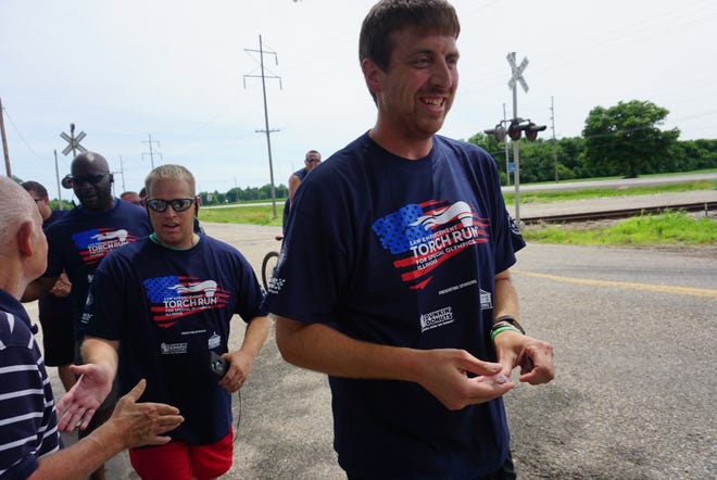Chad Kerns (at front) was greeted by a crowd outside the Logan Mason Rehab Center as he jogged through Lincoln Thursday with a group of Logan County law enforcement officials to "pass the torch" in honor of the Special Olympics. [Photo by The Courier]