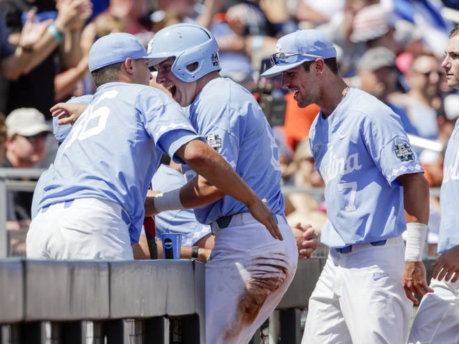 North Carolina's Ike Freeman, center, is greeted at the dugout by Joey Lancellotti (36) and Dallas Tessar (7) after scoring against Oregon State in the third inning on a sacrifice fly by Ashton McGee in an NCAA College World Series baseball game in Omaha, Neb., Saturday, June 16, 2018. (AP Photo/Nati Harnik)