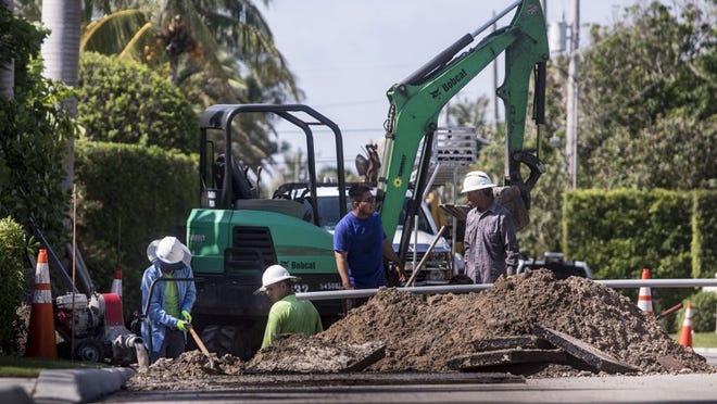 Workers use a backhoe to open up the road along N. Ocean Blvd. just south of Indian Rd. to install cable lines for AT&T Friday, June 8, 2018. A town engineer said the work related to the town-wide utility undergrounding Phase 1-North project is continuing in the area. (Damon Higgins / Daily News)