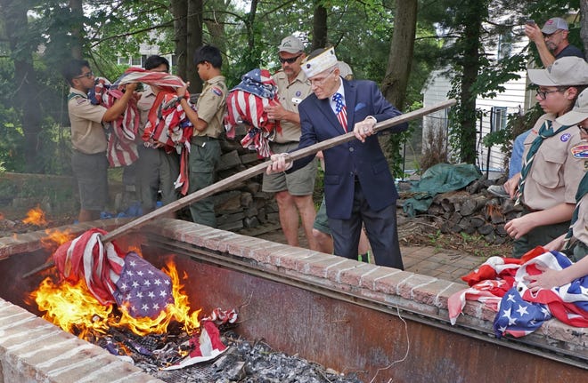 James Geyer, commander of the Lymansville VFW Post 10011, show the Boy Scouts a method of delivering the old flags to the fire during a flag retirement cememony at the North Providence VFW post on Saturday. [The Providence Journal / Sandor Bodo]
