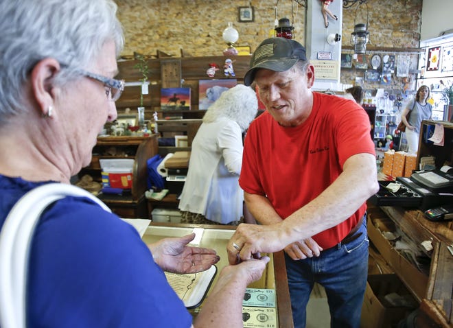 Bob Secord, owner of Kaw River Rustics, completes a customer's transaction during a First Friday Art Walk. [Chris Neal/The Capital-Journal]