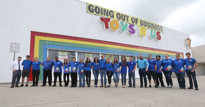 Employees line up for a group photo on Friday at Toys R Us. Past and present employees said the store's staff is like a family, an environment that likely can't be re-created at their next jobs. [PATTI BLAKE/THE NEWS HERALD]