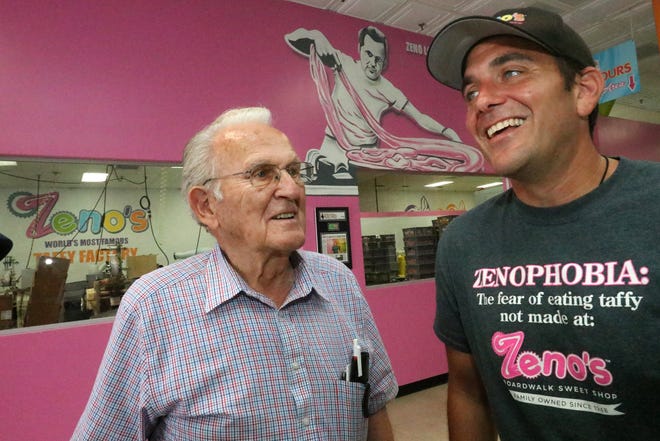 With a mural depicting him pulling taffy over his shoulder, Zeno Louizes looks at his son John Louizes as they talk about 70 years of making taffy at the family business. Zeno's Sweet Shop Factory operates a shop at Sunshine Park Mall in South Daytona, in addition to the Daytona Beach Boardwalk.  [News-Journal/David Tucker]