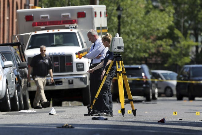 Investigators stand in a street near evidence markers outside the warehouse building where the Art All Night Trenton 2018 festival that was the scene of a shooting that resulted in numerous injuries and at least one death Sunday, June 17, 2018, in Trenton, N.J. (AP Photo/Mel Evans)