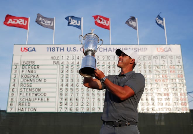 Brooks Koepka holds up the U.S. Open trophy after Sunday's win. [Carolyn Kaster/The Associated Press]