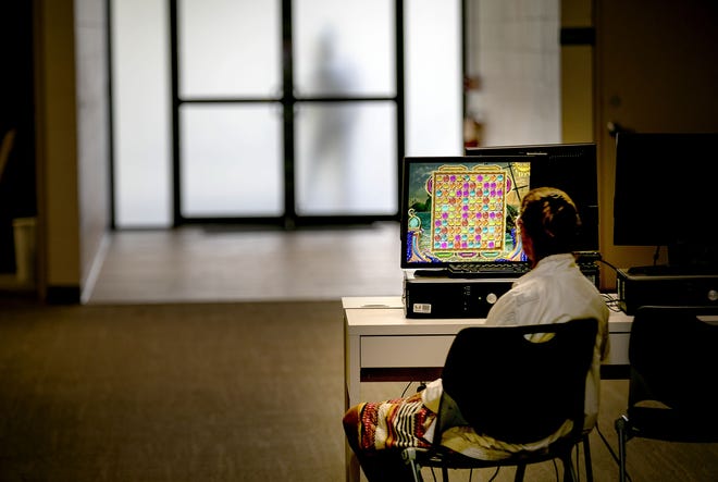 A client in the women's area of the Phoenix House treatment center spends her lunch break quietly playing a game on Monday. The Phoenix House is facing a 40 percent budget cut totaling about $1.6 million. [Alan Youngblood/Staff photographer]