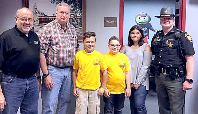 Cambridge fifth-graders selected of winners of the "Sheriff for a Day" essay contest sponsored by Guernsey County Sheriff Jeff Paden include Carter Forshey, Cohen Scarbo and Selina Garcia. The students are pictured with, l to r, Guernsey County Commissioners Dave Wilson and Ernest "Skip" Gardner, and Sheriff's Capt. Jeremy Wilkinson.
