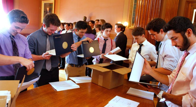Members of the Division 2 champion Chariho Chargers baseball team look over the House of Representatives' citation they received during a visit to the State House Tuesday afternoon. [The Providence Journal / Kris Craig]