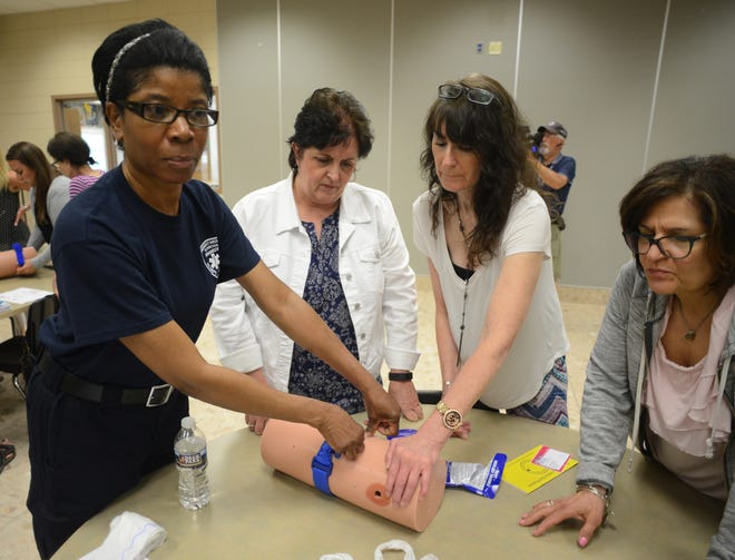 From left, Karen Coe, of Penndel-Middletown Emergency Squad, shows Central Bucks School District nurses Diana Thomas, Robyn Wang and Stella Bredin the proper way to use a tourniquet during a Stop the Bleed training session Wednesday at Central Bucks South High School in Warrington. [WILLIAM THOMAS CAIN/PHOTOJOURNALIST]