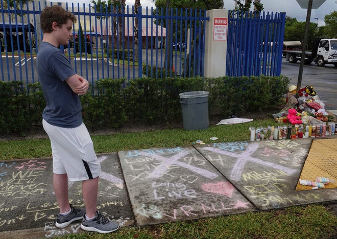 A fan of rap singer XXXTentacion pauses by a memorial, Tuesday, June 19, 2018, outside Riva Motorsports in Deerfield Beach, Fla., where the troubled rapper-singer was killed the day before. The 20-year-old rising star, whose real name is Jahseh Dwayne Onfroy, was shot outside the motorcycle dealership on Monday, June 18, when two armed suspects approached him, authorities said. (Joe Cavaretta/South Florida Sun-Sentinel via AP)