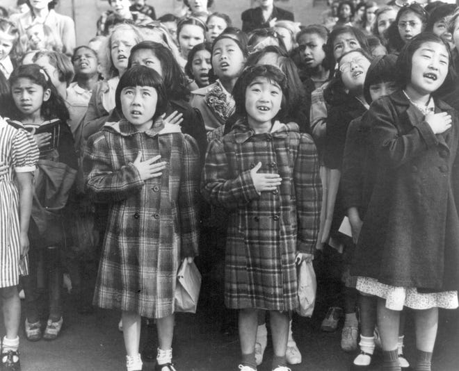 FILE - In this April 1942 file photo made available by the Library of Congress, children at the Weill public school in San Francisco recite the Pledge of Allegiance. Some of them are evacuees of Japanese ancestry who will be housed in War Relocation Authority centers for the duration of World War II. Throughout American history, during times of war and unrest, authorities have cited various reasons and laws to take children away from their parents. Examples include Native American boarding schools, Japanese internment camps and deportations that happened during the Great Depression. (Dorothea Lange/U.S. War Relocation Authority via AP, File)