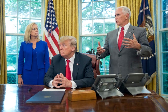 President Donald Trump, center, listens to Vice President Mike Pence, right, address members of the media before signing an executive order to end family separations at the border, during an event in the Oval Office of the White House in Washington, Wednesday, June 20, 2018. Looking on is Homeland Security Secretary Kirstjen Nielsen, left. (AP Photo/Pablo Martinez Monsivais)