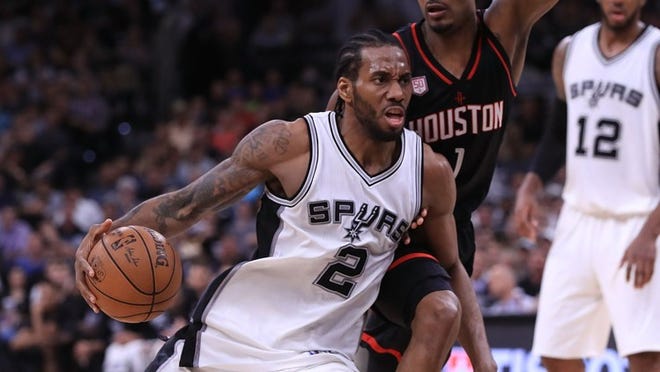 San Antonio’s Kawhi Leonard, driving against Houston’s Trevor Ariza in the 2017 NBA playoffs, has asked the Spurs to trade him after missing most of last season with a quadriceps injury. RONALD MARTINEZ/GETTY IMAGES