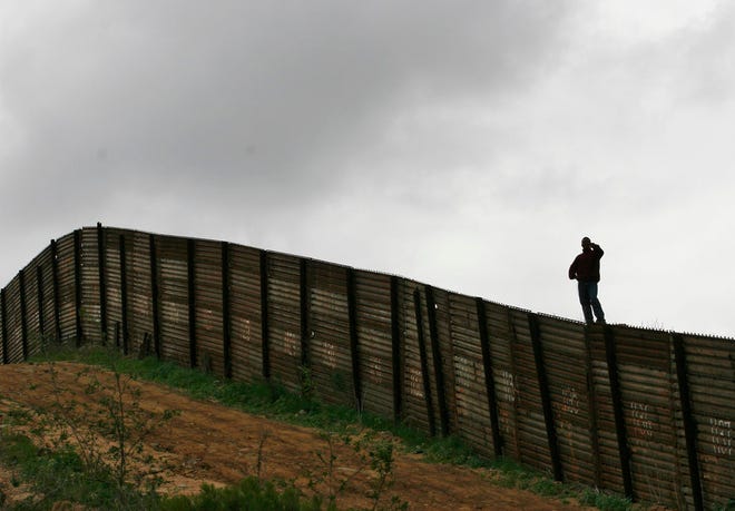 FILE - This April 27, 2006 file photo shows the U.S.-Mexico border fence near Smuggler’s Gulch west of the San Ysidro Port of Entry in San Diego. Twenty-six days after being apprehended on May 23, 2018 at the U.S.-Mexico border with his son, a Brazilian man in detention says he has no idea when he may see his 9-year-old, who he fears is distraught and having difficulty communicating since he only speaks Portuguese.