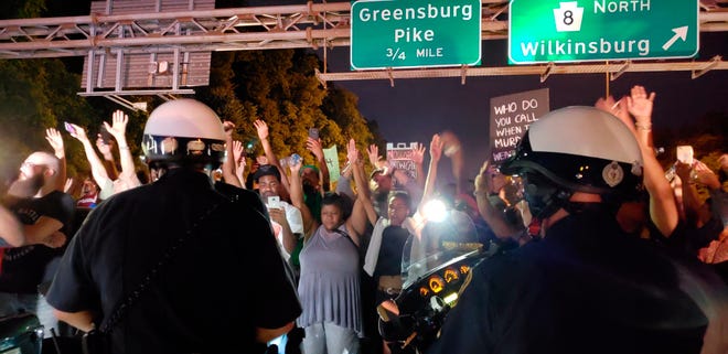 Protesters chant "Hands up! Don't shoot!" at motorcycle officers near the head of a line of vehicles stuck on Interstate 376 in Pittsburgh on Thursday, June 21, 2018. The highway was shut down by the people protesting the East Pittsburgh police after the June 19 shooting death of Antwon Rose, a 17-year-old boy fatally shot by a police officer in Pennsylvania seconds after he fled a traffic stop. He did not pose a threat to anyone, a lawyer for the family of the teen said. (Andrew Goldstein/Pittsburgh Post-Gazette via AP)