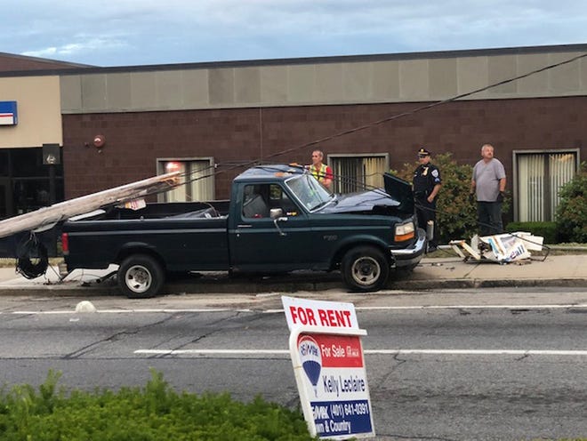 After this truck hit a utility pole on Friday, power lines fell on a car, trapping a woman and two children inside. [The Providence Journal / Mark Reynolds]