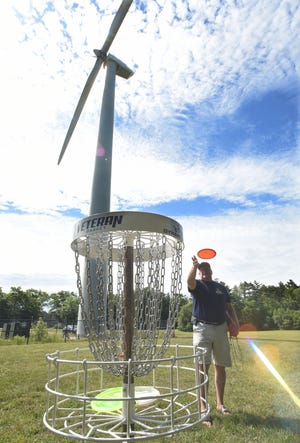 Windmill holes are common on minature gold courses, but UMass Dartmouth has an enormous wind generator next to the ninth green, where, Frank Sherman tries to sink a putt on Thursday. [Jack Foley / Fall River Herald News photo]
