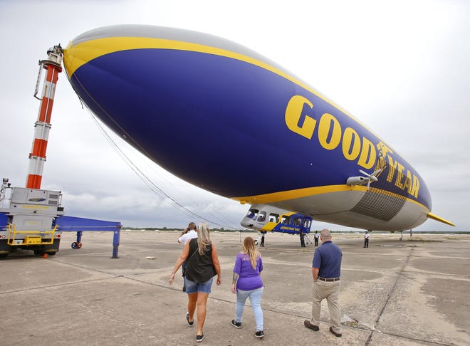 Goodyear employees make their way to the company's Wingfoot One blimp for a ride over the city Friday morning at Forbes Field. [Chris Neal/The Capital-Journal]