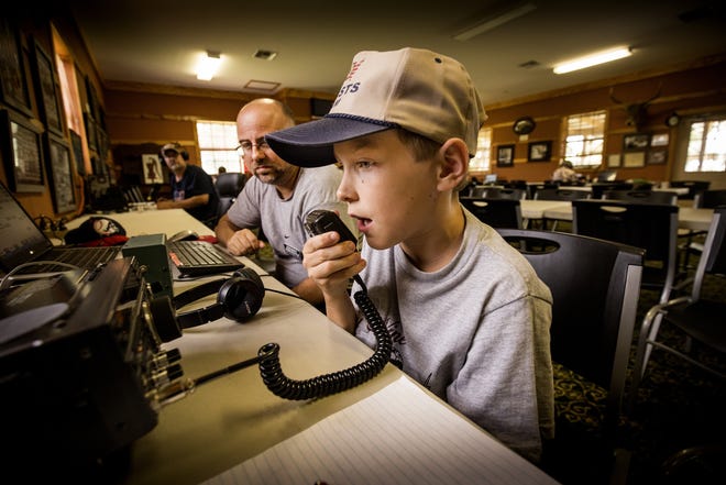 Liam Holzer, right, tries to hail other amateur radio operators across the nation with Kenny Kozla, left, during the Lakeland Amateur Radio Club's Annual ARRL Field Day Event at the Kathleen Area Historical Society Heritage Park in Kathleen on Saturday. Members of the Lakeland Amateur Radio Club demonstrated capabilities at Kathleen Historical Society Heritage Park. [ERNST PETERS/THE LEDGER]